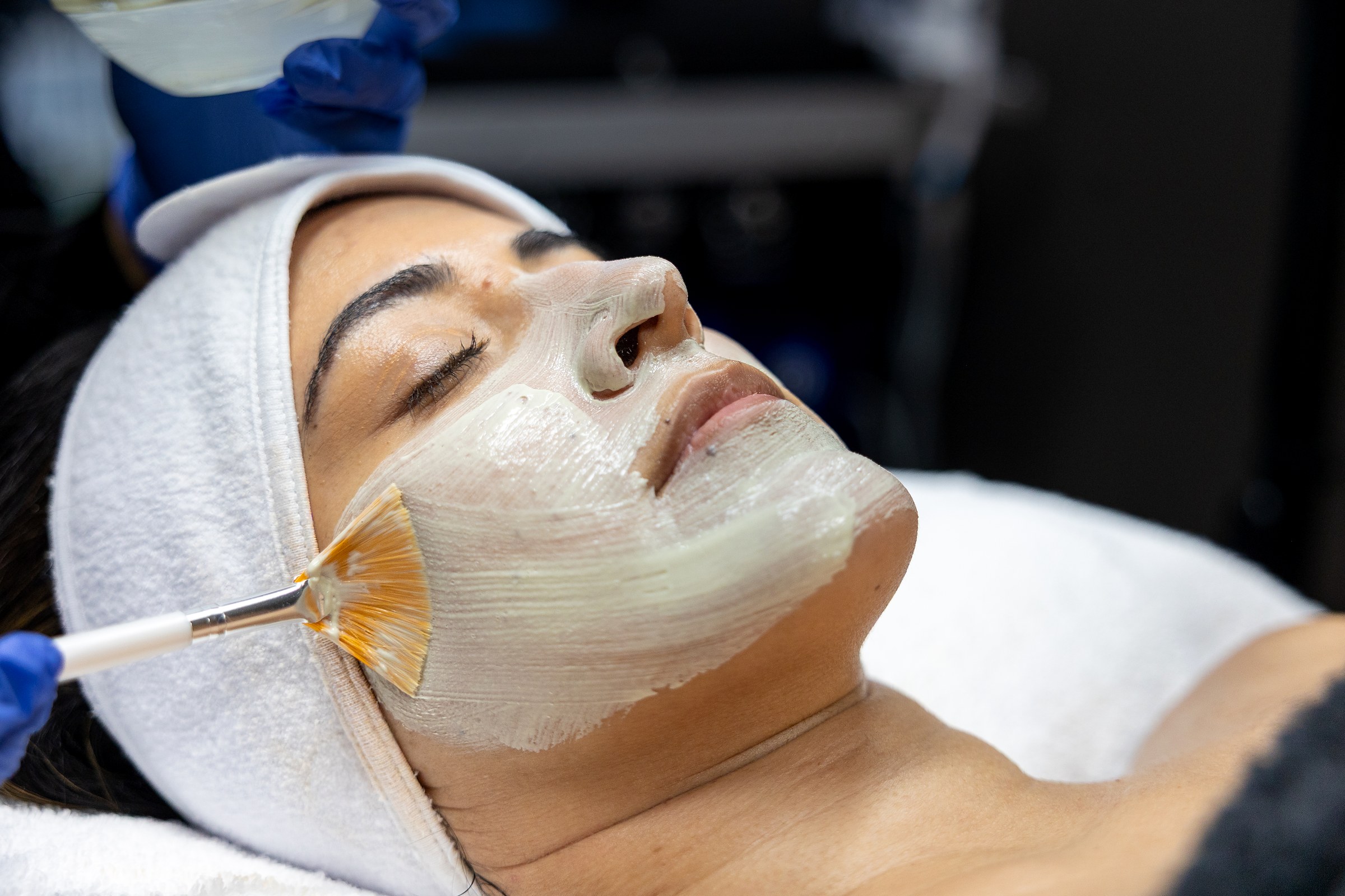 An esthetician applying a facial mask at Wellth
