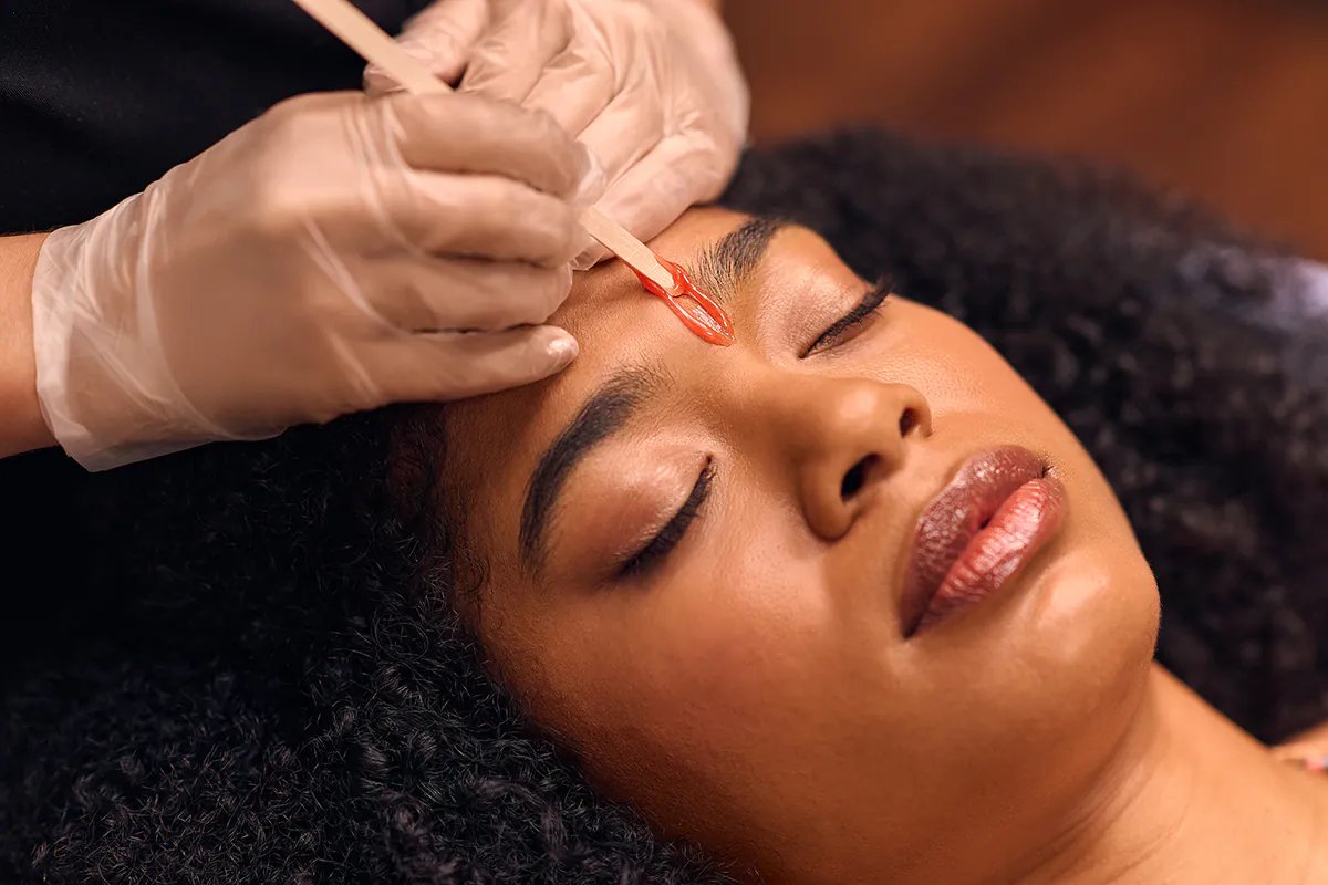 A specialist applying wax to shape a client's eyebrows